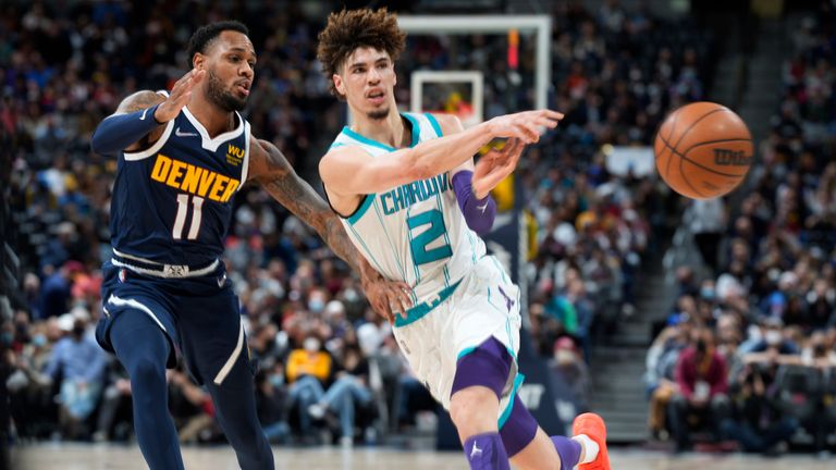 Charlotte Hornets guard LaMelo Ball passes the ball away from Denver Nuggets guard Monte Morris during the first half of an NBA basketball game Thursday, Dec. 23, 2021, in Denver.