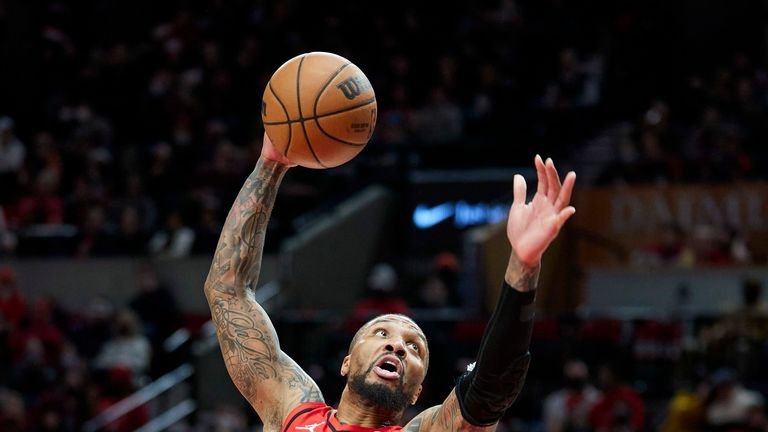 Portland Trail Blazers guard Damian Lillard, center, goes up for a dunk over Charlotte Hornets forward Cody Martin, left, and forward P.J. Washington during the second half of an NBA basketball game in Portland, Ore., Friday, Dec. 17, 2021. (AP Photo/Craig Mitchelldyer)


