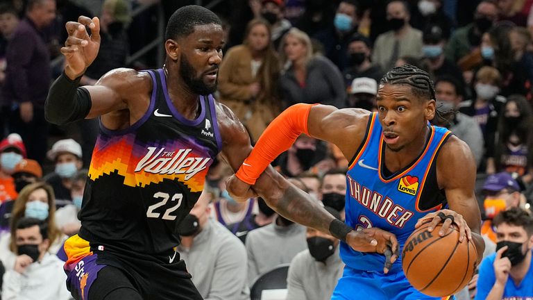 Oklahoma City Thunder guard Shai Gilgeous-Alexander passes in front of Phoenix Suns center Deandre Ayton (22) during the first half of an NBA basketball game, Thursday, December 23, 2021, in Phoenix. 