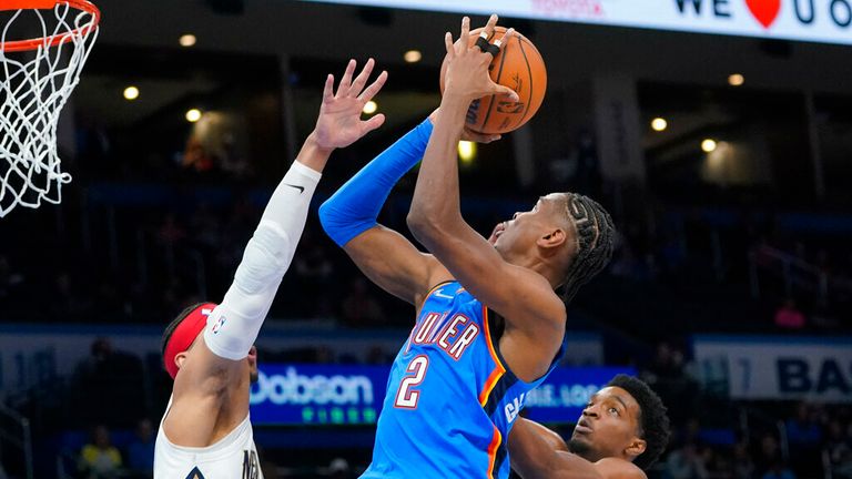 Oklahoma City guard Shai Gilgeous-Alexander (2) shoots between New Orleans Pelicans guard Josh Hart, left, and forward Herbert Jones, right, in the first half of an NBA basketball game Wednesday, Dec. 15, 2021, in Oklahoma City. (AP Photo/Sue Ogrocki)