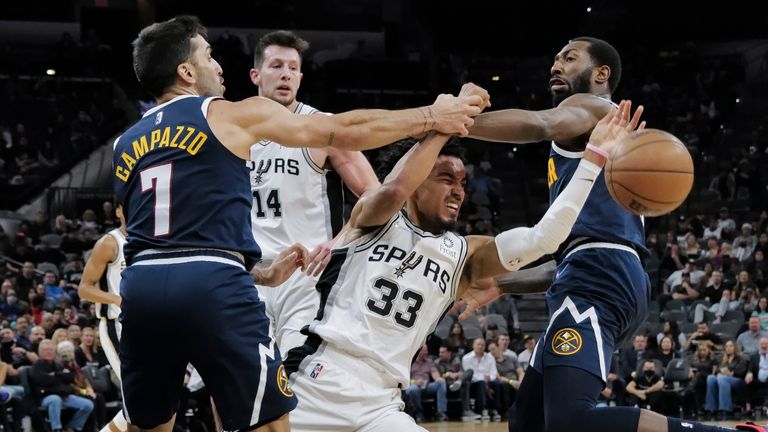 San Antonio Spurs&#39; Tre Jones (33) and Drew Eubanks (14) tangle with Denver Nuggets&#39; Facundo Campazzo (7) and Davon Reed during the second half of an NBA basketball game, Thursday, Dec. 9, 2021, in San Antonio. (AP Photo/Darren Abate)