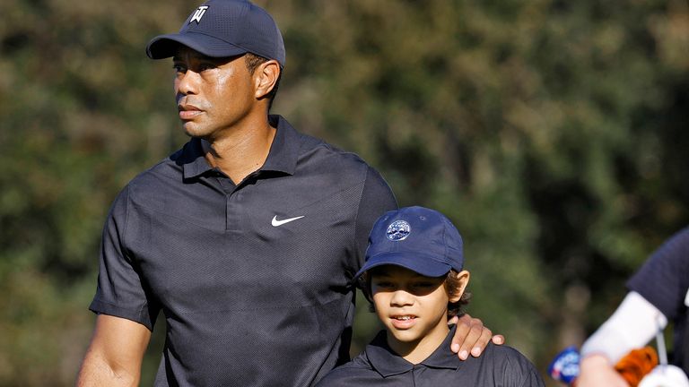 Tiger Woods, left, his son Charlie walk the first fairway during the first round of the PNC Championship golf tournament Friday, Dec. 17, 2021, in Orlando, Fla. Woods is back playing after getting injured in a car accident. He is paired with Charlie during the tournament. (AP Photo/Scott Audette) 