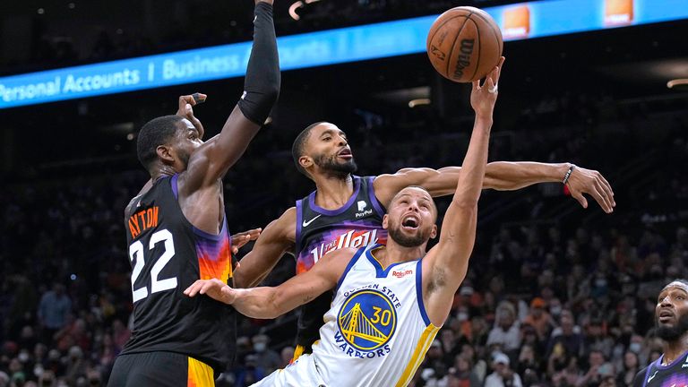 Golden State Warriors guard Stephen Curry shoots between Phoenix Suns center Deandre Ayton and guard Cameron Payne