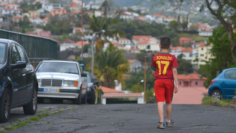 A young boy wearing C.Ronaldo jersey passes trough the neighbourhood where Cristiano Ronaldo and his family used to live, Quinta Falcao, a part of Santo Antonio (English: Saint Anthony), a parish in the northeastern part of Funchal on the island of Madeira..Portuguese football star Cristiano Ronaldo's talent was first revealed in the CF Andorinha, a little club of his native island of Madeira, where pictures of this gifted kid, who became inspiration, are today displayed everywhere.