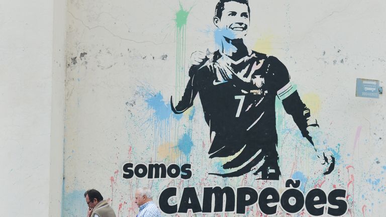 People pass in front of Cristiano Ronaldo mural 'We're Champions' in Funchal on the island of Madeira, where Portuguese football star Cristiano Ronaldo grew up and played for amateur team Andorinha from 1992 to 1995. On Thursday, April 26, 2018, in Funchal, Madeira Island, Portugal.