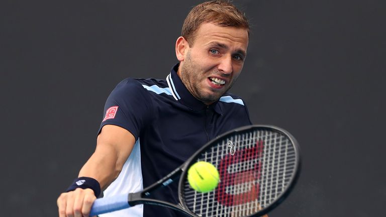 Dan Evans of Britain plays a backhand return to David Goffin of Belgium during their first round match at the Australian Open tennis championships in Melbourne, Australia, Tuesday, Jan. 18, 2022. (AP Photo/Tertius Pickard)