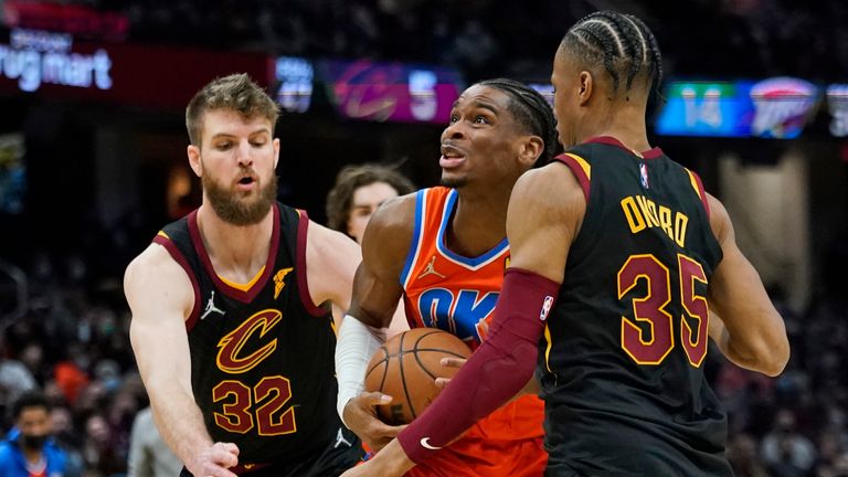 Oklahoma City Thunder&#39;s Shai Gilgeous-Alexander, center, drives between Cleveland Cavaliers&#39; Dean Wade, left, and Isaac Okoro in the second half of an NBA basketball game, Saturday, Jan. 22, 2022, in Cleveland. (AP Photo/Tony Dejak)