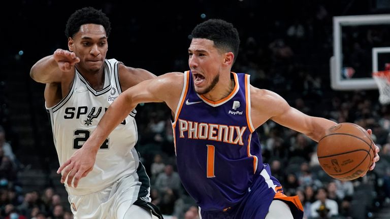 Phoenix Suns guard Devin Booker (1) drives around San Antonio Spurs guard Devin Vassell (24) during the second half of an NBA basketball game, Monday, Jan. 17, 2022, in San Antonio. 