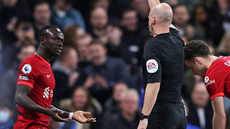 Referee Anthony Taylor shows a yellow card to Sadio Mane for his foul on Cesar Azpilicueta