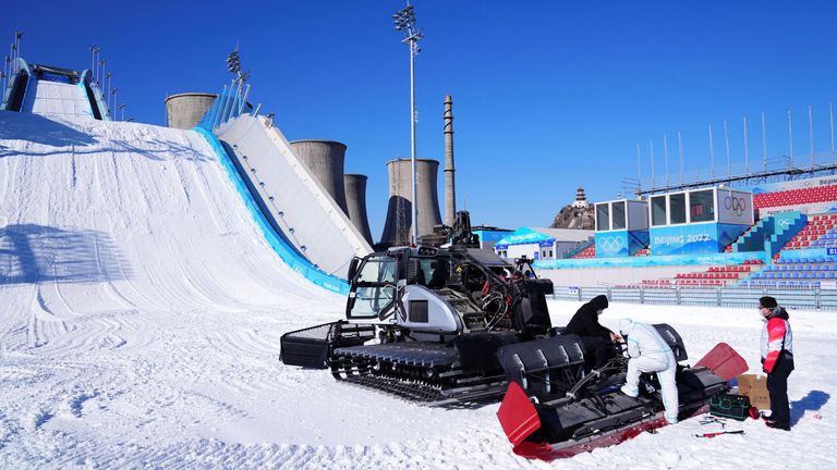 Officials check on an artificial snowfall machine at the Big Air Shougang Winter Olympics venue (AP)