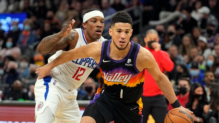 Phoenix Suns guard Devin Booker (1) drives past Los Angeles Clippers guard Eric Bledsoe during the first half of an NBA basketball game Thursday, Jan. 6, 2022, in Phoenix.