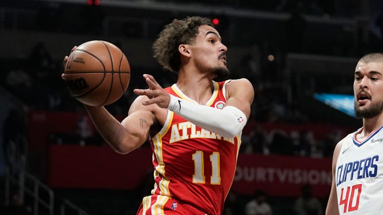 Atlanta Hawks' Trae Young, center, passes the ball as he is pressured by Los Angeles Clippers' Ivica Zubac (40) during first half of an NBA basketball game Sunday, Jan. 9, 2022, in Los Angeles. (AP Photo/Jae C. Hong)