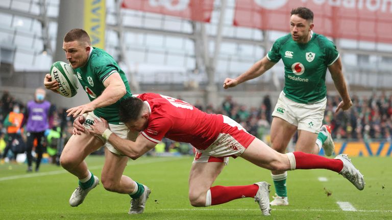 Ireland's Andrew Conway, left goes over the line to score a try as he is tackled by Wales' Josh Adams 