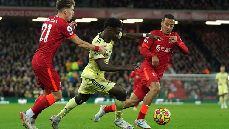 Bukayo Saka is challenged by Liverpool's Kostas Tsimikas and Thiago (AP)