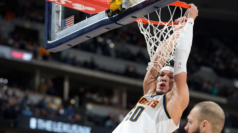 Denver Nuggets forward Aaron Gordon hangs from the rim after dunking for a basket over New York Knicks guard Evan Fournier 