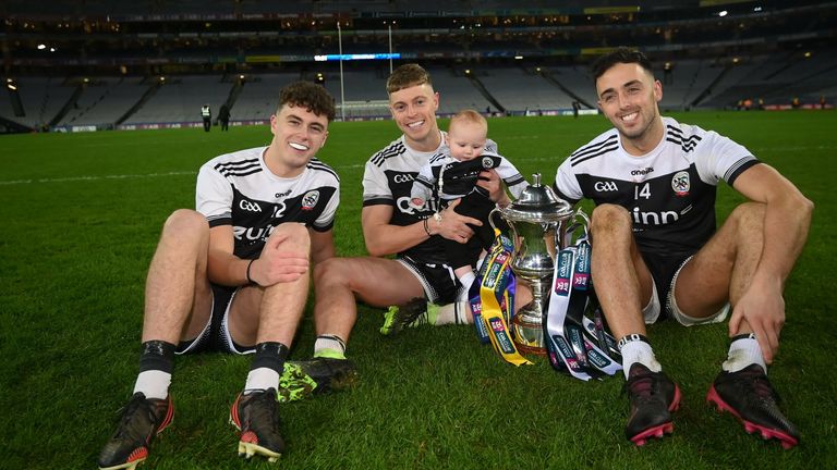 12 February 2022; Kilcoo players, from left, Shealin Johnston, Jerome Johnston and his 5-month-old son Lar, and Ryan Johnston celebrate with the Andy Merrigan cup after the AIB GAA Football All-Ireland Senior Club Championship Final match between Kilcoo, Down, and Kilmacud Crokes, Dublin, at Croke Park in Dublin. Photo by Stephen McCarthy/Sportsfile