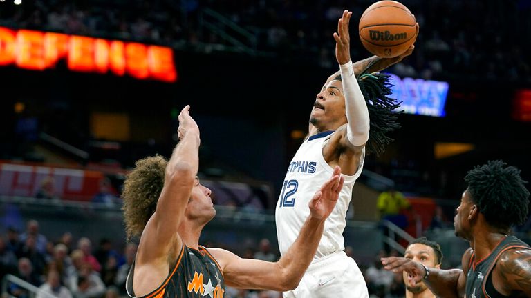Memphis Grizzlies guard Ja Morant (12) passes over Orlando Magic center Robin Lopez (33) for a dunk during the second half of an NBA basketball game, Saturday, February 5, 2022 , in Orlando, Fla. (AP Photo/John Raoux)