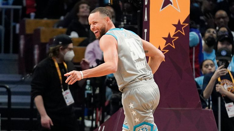 Golden State Warriors&#39; Stephen Curry smiles as he points to the bench after hitting another three-point shot during the second half of the NBA All-Star basketball game, Sunday, Feb. 20, 2022, in Cleveland. 
