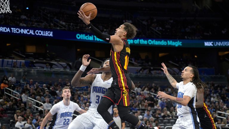 Atlanta Hawks guard Trae Young (11) goes up for a shot in front of Orlando Magic forward Franz Wagner (22), center Wendell Carter Jr. (34) and guard Cole Anthony (50) during the first half of an NBA basketball game,