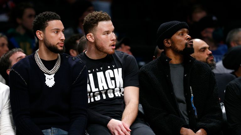 Brooklyn Nets  Ben Simmons , Blake Griffin and  Kevin Durant (7) watch play against the Boston Celtics from the bench,  during the first half of an NBA basketball game, Thursday, Feb. 24, 2022 in New York. .(AP Photo/Noah K. Murray)                                                                           