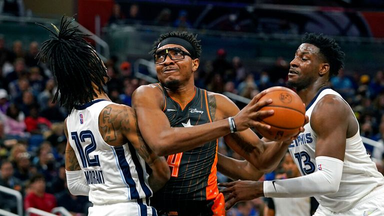 Orlando Magic center Wendell Carter Jr., center, goes up for a shot as he gets between Memphis Grizzlies guard Ja Morant (12) and forward Jaren Jackson Jr. (13) during the first half of an NBA basketball game, Saturday, Feb. 5, 2022, in Orlando, Fla. (AP Photo/John Raoux)