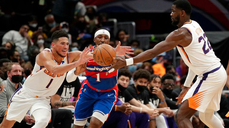 Washington Wizards&#39; Kentavious Caldwell-Pope, center, knocks the ball away on a pass-attempt by Phoenix Suns&#39; Deandre Ayton (22) to Devin Booker, left, during the second half of an NBA basketball game, Saturday, Feb. 5, 2022, in Washington. (AP Photo/Luis M. Alvarez)