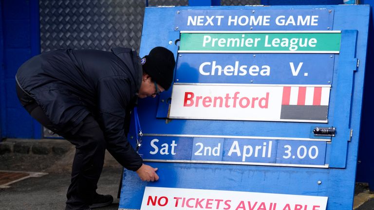 Un membre du personnel au sol ajuste un tableau de match à venir avant le match de football de la Premier League anglaise entre Chelsea et Newcastle United au stade de Stamford Bridge à Londres, le dimanche 13 mars 2022