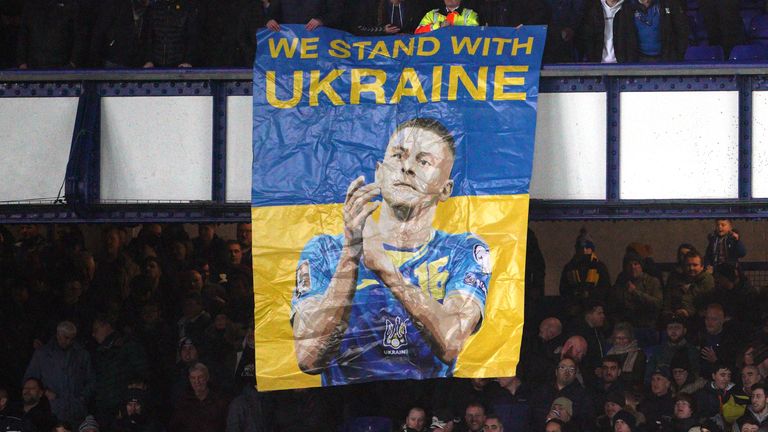 Fans in the stands with a banner of Everton's Vitaliy Mykolenko reading "we stand with Ukraine"