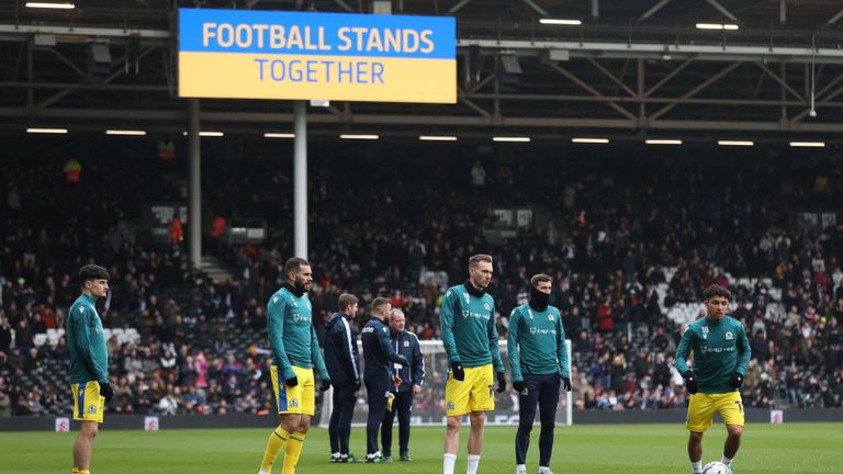 Blackburn players warm up in front of the screen showing a Ukrainian flag to indicate peace and sympathy