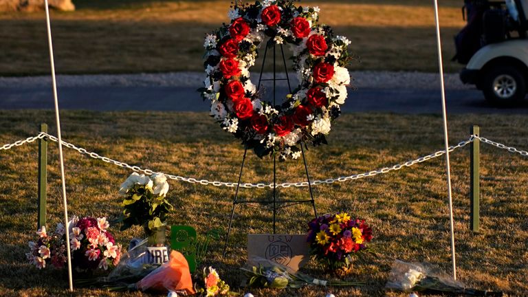 A golfer drives by a makeshift memorial at the Rockwind Community Links Wednesday, March 16, 2022, in Hobbs, New Mexico. The memorial was for student golfers and the coach of University of the Southwest  killed in a crash in Texas. (AP Photo/John Locher)
