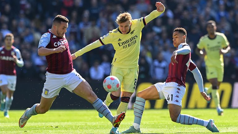 Martin Oedegaard of Arsenal is challenged by John McGinn and Jacob Ramsey of Aston Villa