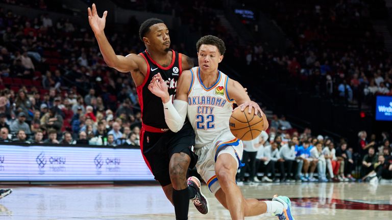 Oklahoma City Thunder forward Isaiah Roby, right, dribbles past Portland Trail Blazers forward Elijah Hughes during the second half of an NBA basketball game in Portland, Ore., Monday, March 28, 2022. 