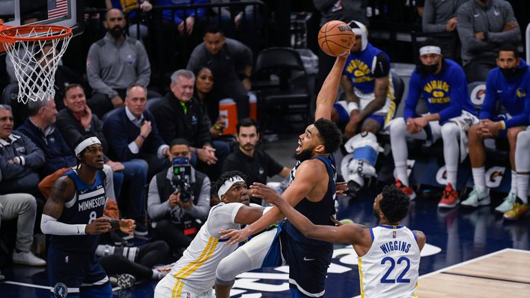 Minnesota Timberwolves center Karl-Anthony Towns goes up for a shot over Golden State Warriors center Kevon Looney, left, as Warriors forward Andrew Wiggins