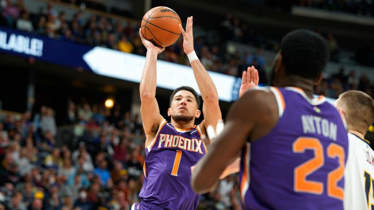 Phoenix Suns guard Devin Booker shoots as center Deandre Ayton, front, and Denver Nuggets center Nikola Jokic watch during the second half of an NBA basketball game Thursday, March 24, 2022, in Denver. (AP Photo/David Zalubowski)