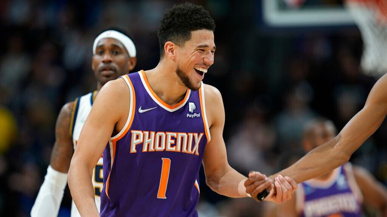 Phoenix Suns guard Devin Booker jokes with teammates, next to Denver Nuggets forward Will Barton during the second half of an NBA basketball game Thursday, March 24, 2022, in Denver. (AP Photo/David Zalubowski)


