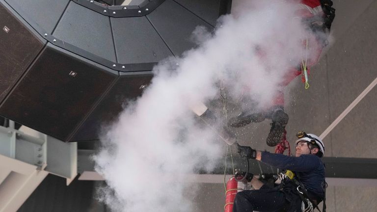 A fire extinguisher is used on a group of speakers that hang from the ceiling of the arena after play was suspended and the building was evacuated