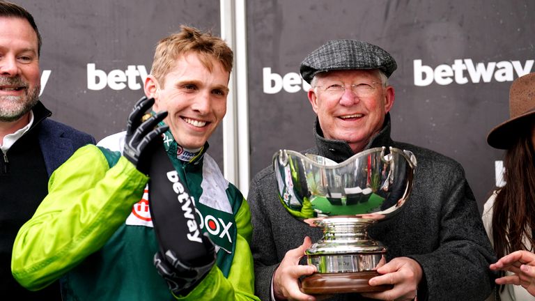 Sir Alex Ferguson holds aloft the Betway Bowl trophy after Clan Des Obeaux's victory at Aintree