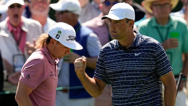 Scottie Scheffler pumps his fist as walks past Cameron Smith  after a birdie chip on the third hole