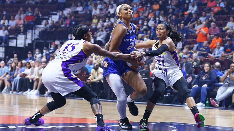 Connecticut Sun guard DiJonai Carrington drives to the basket against Los Angeles Sparks guard Brittney Sykes and Los Angeles Sparks guard Jordin Canada