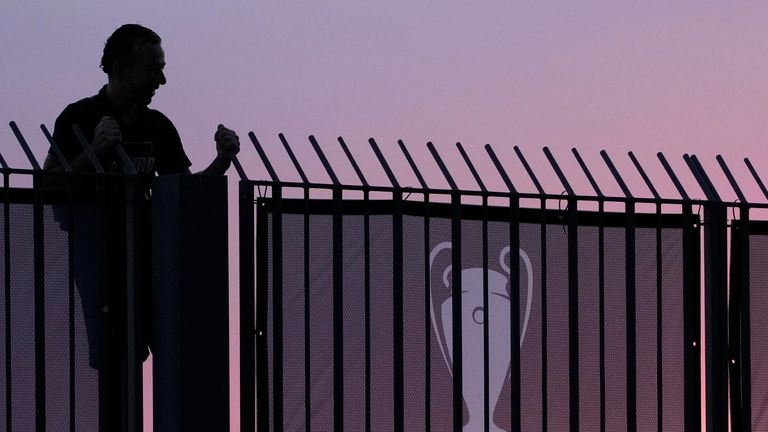 A fan stands on the fence in front of the Stade de France 