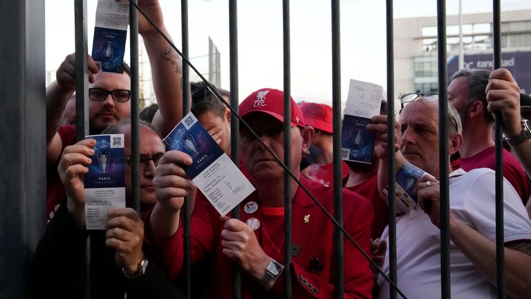 Liverpool fans show tickets and wait outside the gates
