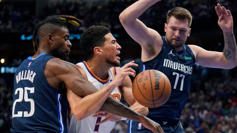 Phoenix Suns guard Devin Booker (1) is fouled by Dallas Mavericks forward Reggie Bullock (25) as guard Luka Doncic (77) looks on during the first half of Game 6 of an NBA basketball second-round playoff series Thursday, May 12, 2022, in Dallas. (AP Photo/Tony Gutierrez)


