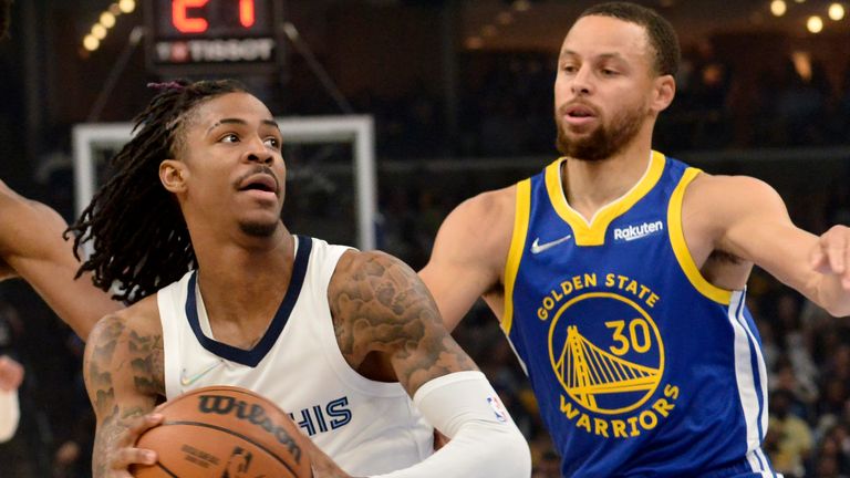 Ja Morant moves towards the basket as Stephen Curry stays in close attention behind him