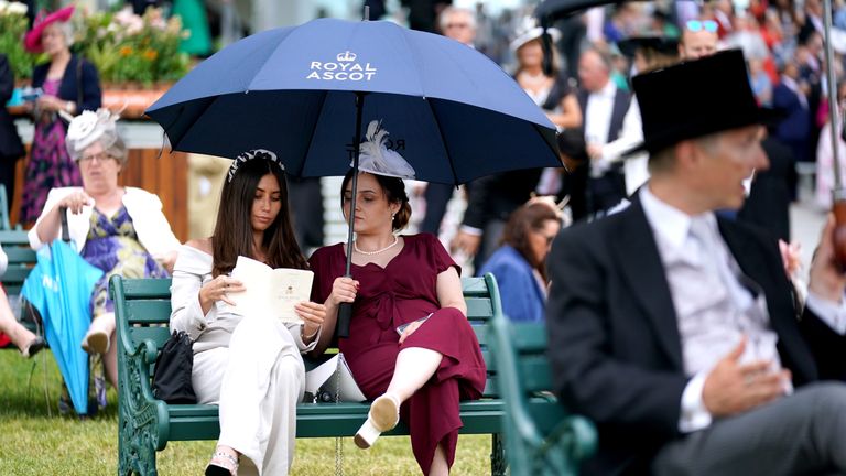 Racegoers take shelter under umbrellas at Royal Ascot
