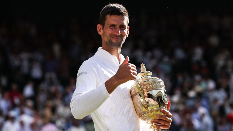Serbia&#39;s Novak Djokovic smiles as he holds his trophy after defeating Australia&#39;s Nick Kyrgios during the men&#39;s singles final tennis match on the fourteenth day of the 2022 Wimbledon Championships at The All England Tennis Club in Wimbledon, southwest London, on July 10, 2022. - RESTRICTED TO EDITORIAL USE (Photo by Adrian DENNIS / AFP) / RESTRICTED TO EDITORIAL USE (Photo by ADRIAN DENNIS/AFP via Getty Images)