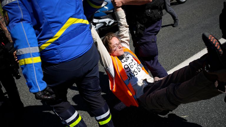 French gendarmes detain a climate activist after a group of demonstrators caused the race to be temporarily immobilised on Stage 10 