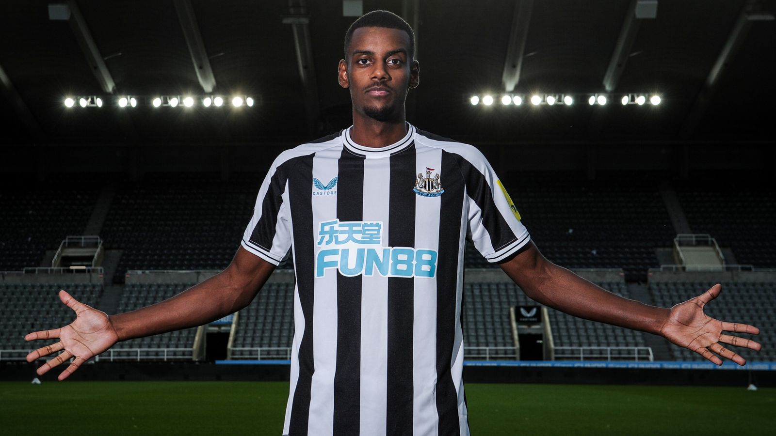  A photo of Alexander Isak, a Swedish professional footballer who plays as a striker for Premier League club Newcastle United, posing in a black and white striped shirt with his arms outstretched.