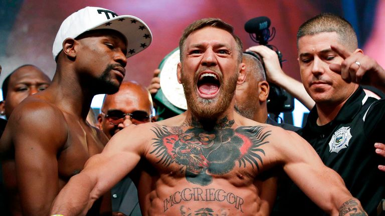 Conor McGregor, center, stands next to Floyd Mayweather Jr., center left, during their weigh-in the day before their boxing match in Las Vegas.