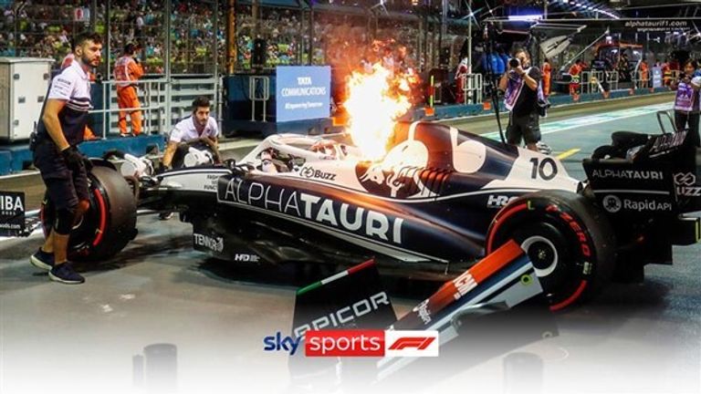 Pierre Gasly jumps out of his car as flames shoot out of the air vent after he pulled into the pits at the Singapore Grand Prix