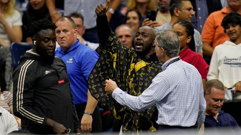 Un aficionado, en el centro, es sacado de su asiento después de intentar cortarse el pelo durante los cuartos de final del campeonato de tenis del US Open entre Nick Kyrgios, de Australia, y Karen Khachanov, de Rusia, el martes 6 de septiembre de 2022 en New York.  (Foto AP/Charles Krupa)